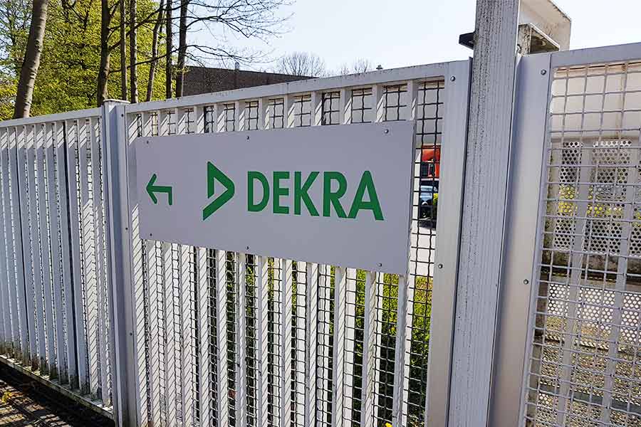 Alu-Dibond Schild der Dekra Bochum. Mit Montage an einem Zaun